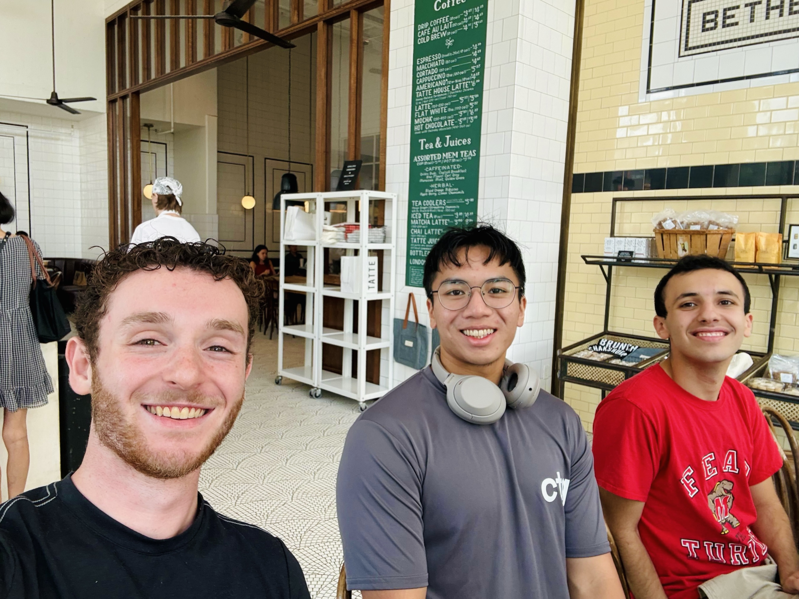 John and two co-interns smiling together at a cafe during the Capital Technology Group internship.